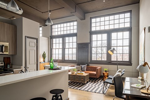 a living room with large windows and a kitchen with a table and chairs